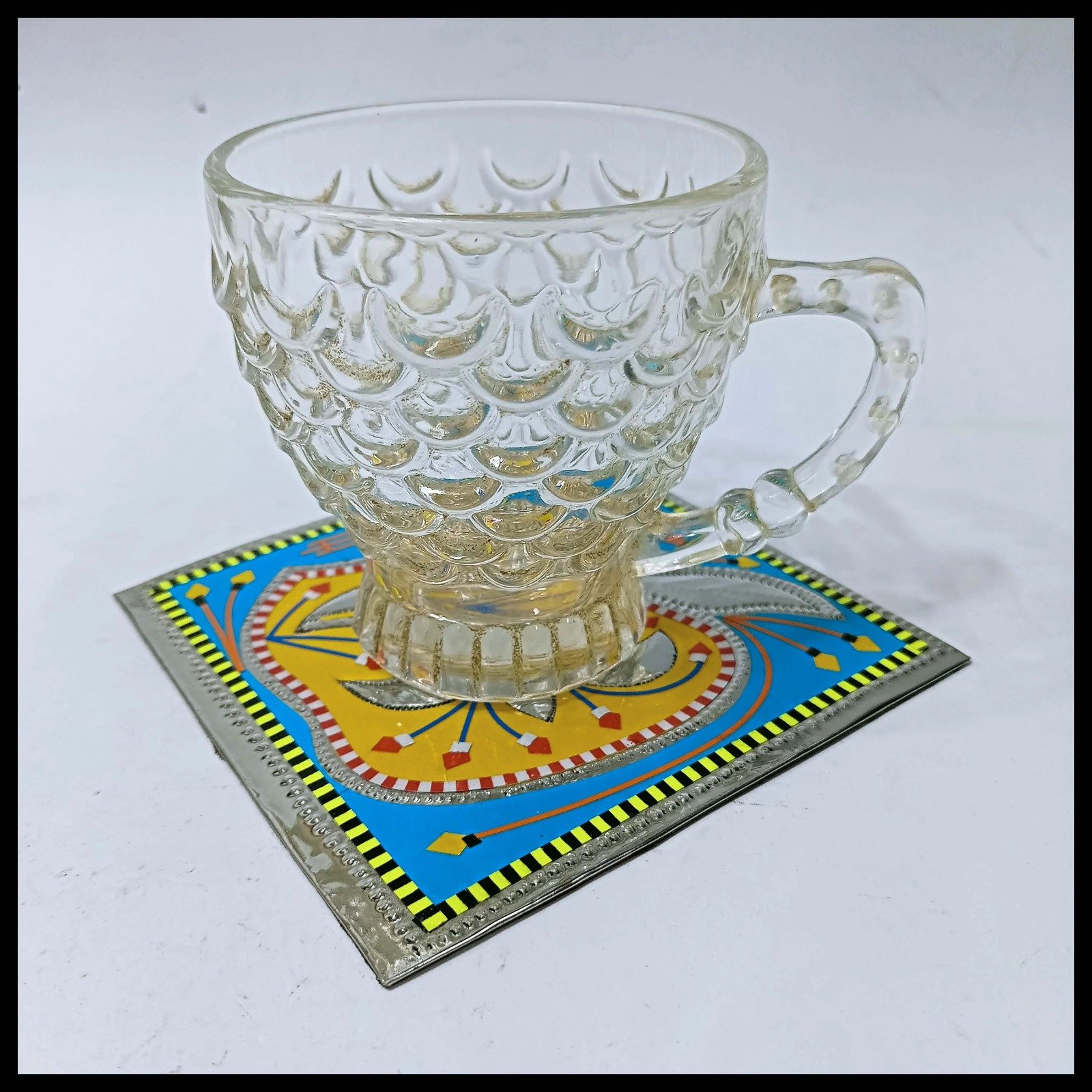 Transparent cup placed on a blue Chamakpatti coaster