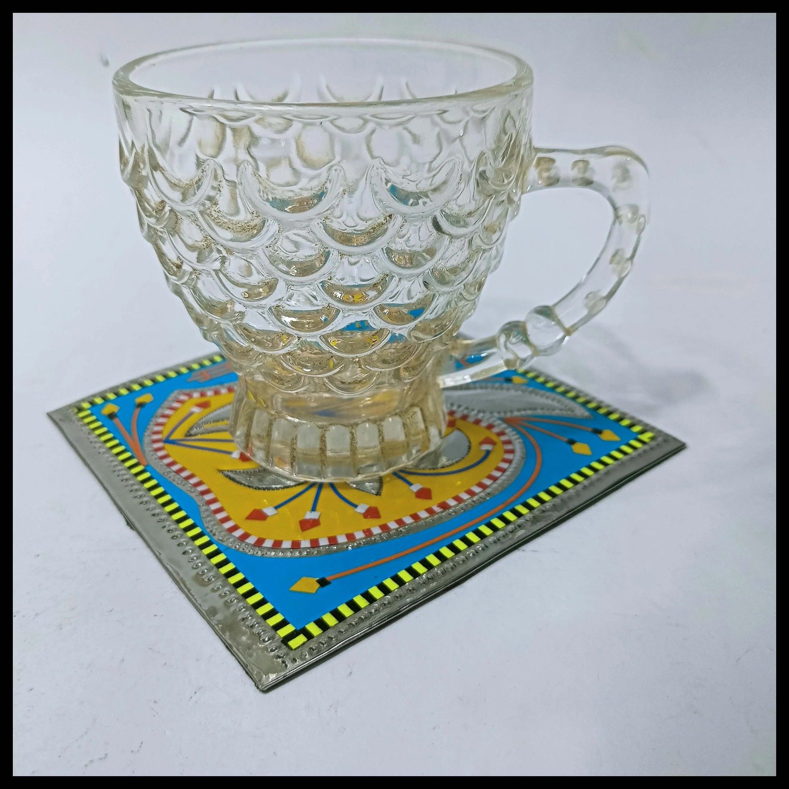 Glass teacup resting on vibrant Chamakpatti coaster